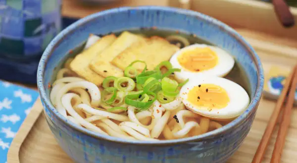 Herzhafte Udon-Nudelsuppe mit pochiertem Ei, Tofu und Frühlingszwiebeln. Ein einfaches Udon-Nudel-Rezept für ein köstliches Essen.