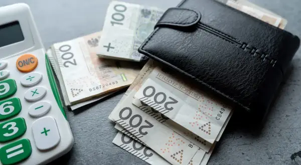 Portfel z pieniędzmi i kalkulatorem. Zastanawiasz się, inflacja co to? Obrazek pokazuje, jak pieniądze mogą szybko znikać.