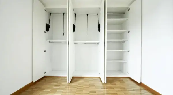Armadio bianco con ante aperte, barre appendiabiti e ripiani. Ottime idee ripostiglio in cartongesso per organizzare ogni spazio.