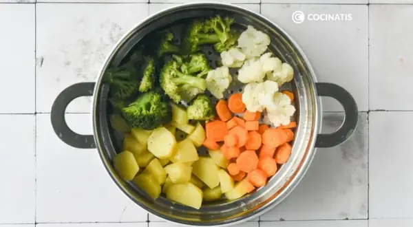 Un vaporizador lleno de un colorido panache de verduras: brócoli, coliflor, zanahorias y patatas cortadas.