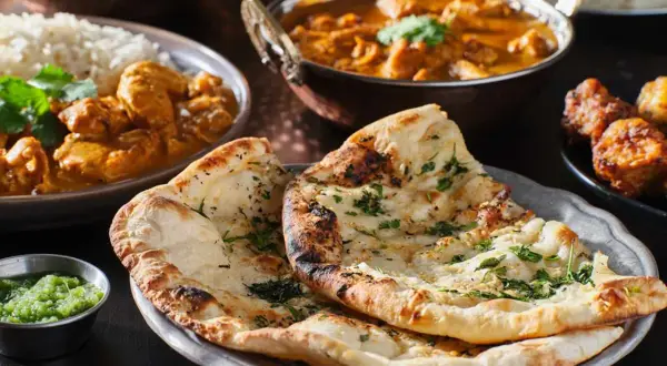 En härlig måltid med indisk mat, inklusive naanbröd, ris och curry. Perfekt för en kväll med vin till indisk mat.
