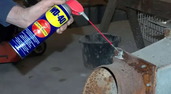 WD-40 wird auf einen verrosteten Kaminofen gesprüht, um Rost zu entfernen.