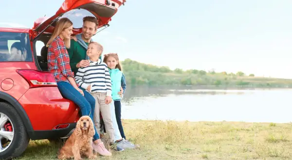 Famille heureuse avec leur chien près d'un lac, profitant d'un voyage dans un pays dog friendly.