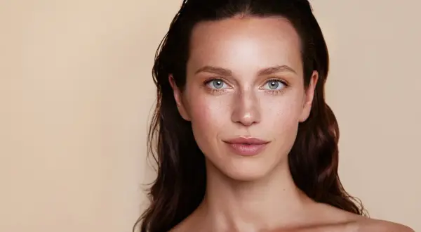 Un maquillage subtil pour agrandir les yeux, mettant en valeur des iris bleus et des taches de rousseur naturelles.