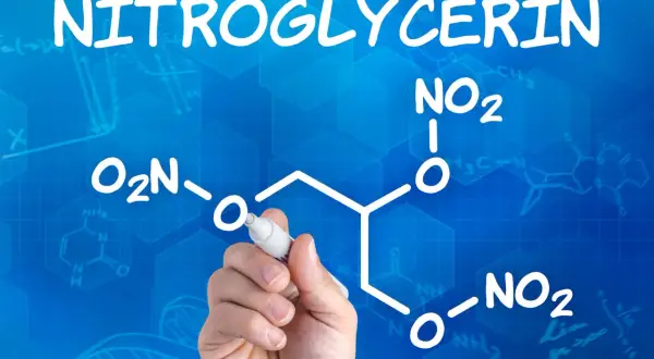 Ręka pisze wzór chemiczny nitrogliceryny na niebieskim tle z siatką i innymi wzorami.