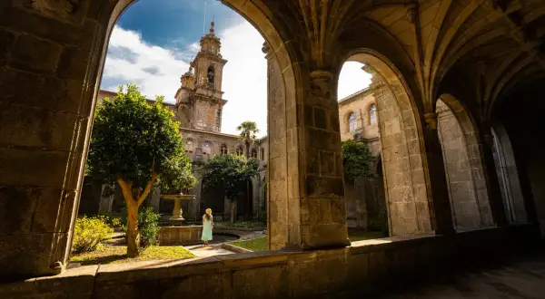 Una mujer contempla el patio interior del monasterio de Poio, con su fuente y campanario al fondo.