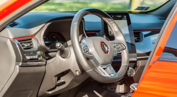 Nowoczesne renault arkana wnętrze z ekranem multimedialnym i kierownicą obszytą skórą. Czerwone akcenty dodają sportowego charakteru.