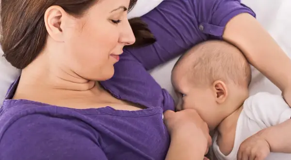 En mamma ammar sitt barn i en liggande position, en av många olika amningspositioner.