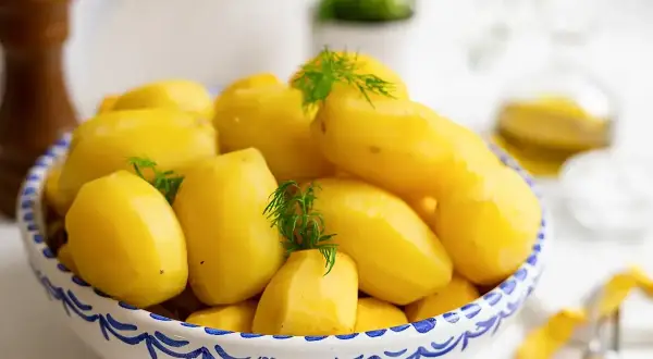 En skål med nykokta, gula potatisar, garnerade med dill. Perfekt för att koka potatis till middagen.