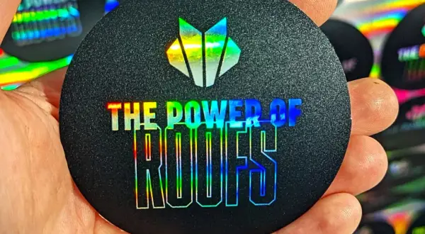 Okrągły czarny naklejka z holograficznym logo i napisem "THE POWER OF ROOFS".
