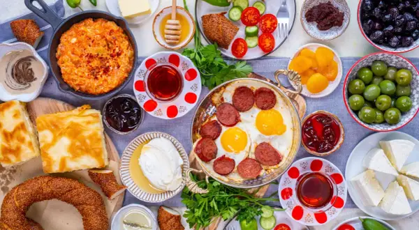 Reichhaltiges türkisches Frühstück: Eier mit Sucuk, Käse, Oliven, Honig und Gebäck. Welches Lebensmittel hat die meisten Kalorien? Wahrscheinlich das Gebäck oder die Wurst.