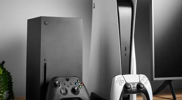 Konsola Xbox Series X i PlayStation 5 z kontrolerami na drewnianym stole.