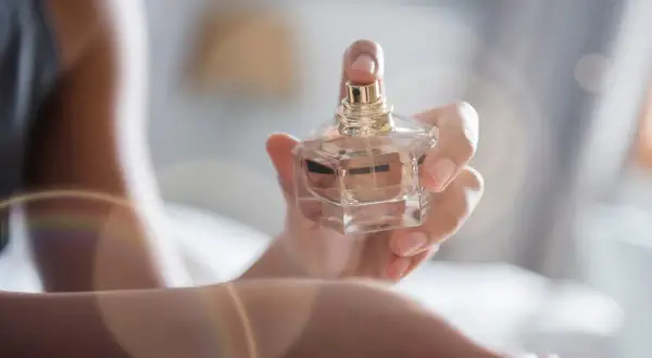 Dłoń trzyma flakonik perfum, a subtelny zapach unosi się w powietrzu. Envy me, Gucci.