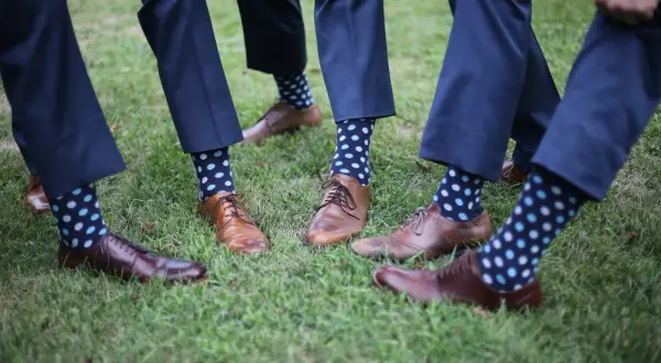Elegancki granatowy garnitur i brązowe buty, a do tego zabawne skarpetki w kropki. Idealny zestaw na ślub.