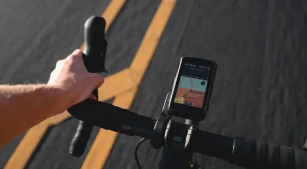 Dłoń na kierownicy roweru, nawigacja pokazuje mapę tras rowerowych w Krakowie.
