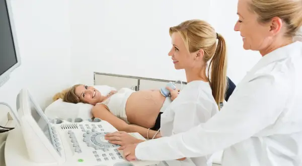 Ciężarna kobieta na USG. Czy do ginekologa trzeba mieć skierowanie od lekarza rodzinnego? Lekarka wykonuje badanie.