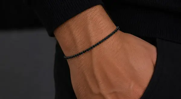 Pulsera barbada oro con diamantes negros en muñeca masculina. Elegancia y estilo en cada detalle.