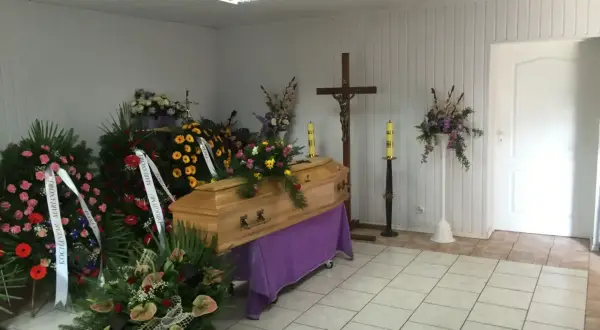 Drewniana trumna otoczona wieńcami i bukietami. Piękne kwiaty na trumnę tworzą smutną, ale pełną szacunku atmosferę.