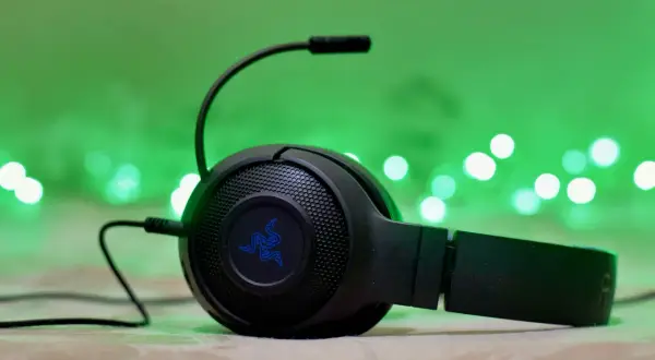 Słuchawki gamingowe Razer z mikrofonem, podłączone przez combo jack, na tle zielonych światełek.