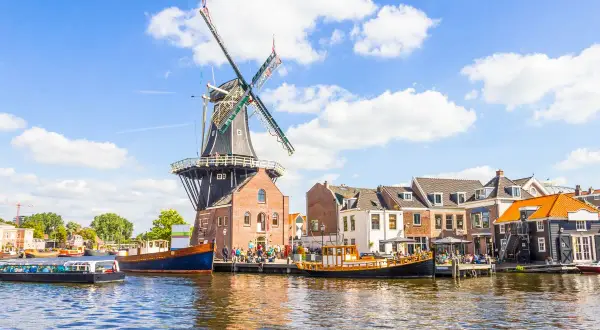 Un moulin à vent historique domine un canal bordé de maisons pittoresques. Une idée de que faire aux Pays-Bas : flâner le long de l'eau.