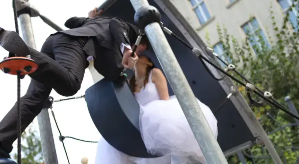 Młoda para w ślubnych strojach całuje się na placu zabaw. Czy lakarnum ma narzeczoną? Tak, i to piękną!