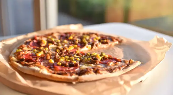 Pyszna pizza z kukurydzą i salami, dzieło mistrza pizzaiolo, leży na papierze.
