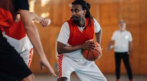 Un joueur de basket concentré, ballon en main, en plein match. Le basket fait-il grandir ? Peut-être pas en taille, mais en esprit d'équipe !