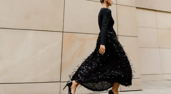 Elegancka kobieta w czarnej sukience z cekinami i piórkami, czarne szpilki. Idealne dodatki do czarnej cekinowej sukienki.