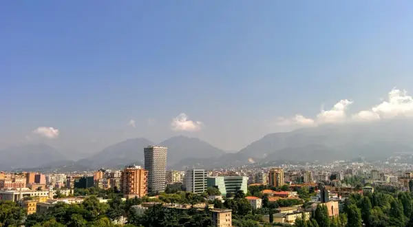 Widok na miasto z górami w tle. Widać nowoczesne budynki i zieleń. To ekuz Albania.