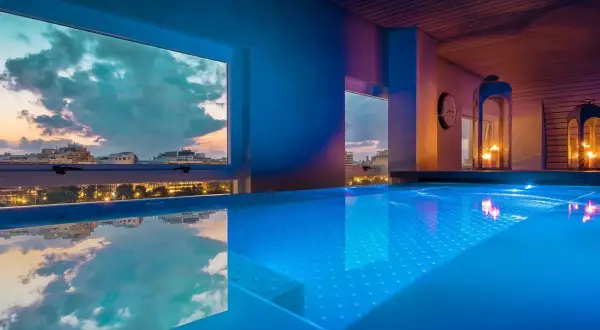 Piscina iluminada con vistas al atardecer de la ciudad. Un lugar perfecto para un día de spa en Valencia.