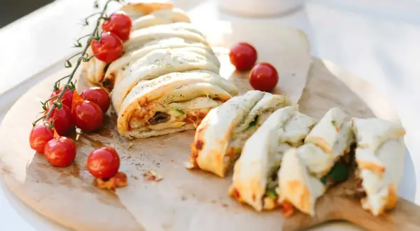 Ein köstlicher Stromboli, gefüllt mit Tomaten, Oliven und Käse, wird mit frischen Kirschtomaten garniert. Perfekt zum Stromboli essen!