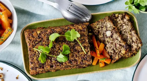 Herzhaftes Linsen-Nuss-Brot mit glasierten Karotten – ein köstliches vegetarisches Weihnachtsessen, garniert mit frischer Petersilie.
