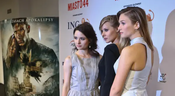 Trzy aktorki z obsady Miasto 44 na ściance. W tle plakat filmu i logo sponsorów.