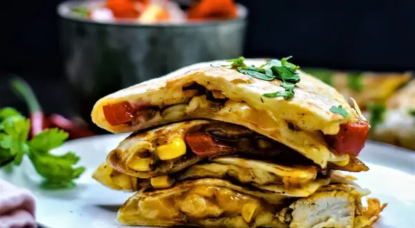 Gestapelte Quesadillas mit Hähnchen, Mais und Tomaten, garniert mit Koriander. So sieht eine leckere Quesadilla aus!