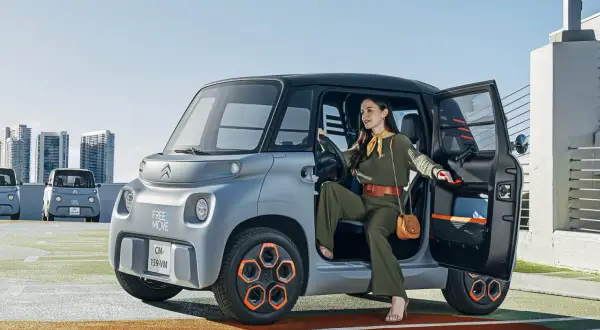 Donna scende da una Citroën Ami, un veicolo elettrico compatto. Le sue prestazioni sono ideali per la città.
