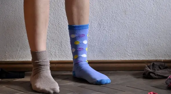 Dwie nogi w skarpetkach: jedna beżowa, druga niebieska w kropki. Dylemat: jakie skarpetki do jasnych spodni?