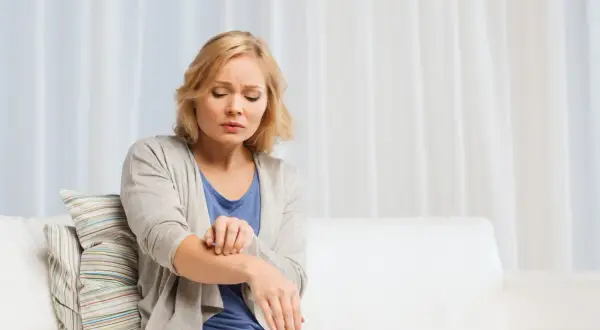 Donna si gratta il braccio, sofferente per l'aria secca che le irrita la pelle.