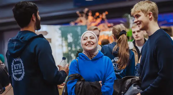 Glada studenter på en mässa, kanske för att välja linjer på gymnasiet. En kvinna i hijab ler stort.