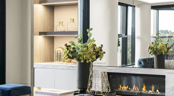 Un elegante camino bioetanolo come funziona: fiamme vive su un letto di sassi bianchi, con decorazioni moderne e arredi di lusso.