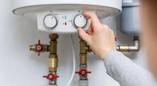 Main tenant ajuste le chauffe-eau pour éviter la pression d'eau chaude.