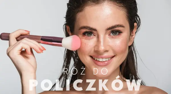 Uśmiechnięta kobieta z pędzlem do różu na policzku. Dowiedz się, jak nakładać róż dla naturalnego efektu.