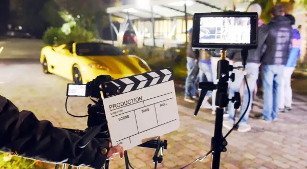 Na planie filmowym, gdzie kręcono scenę z żółtym sportowym autem, klaps filmowy zapowiada, ile zarabiają statyści na planach filmów Patryka Vegi i innych hitów.