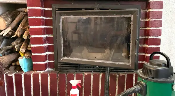Preparativos para como deshollinar una chimenea: leña, aspiradora y spray limpiador.