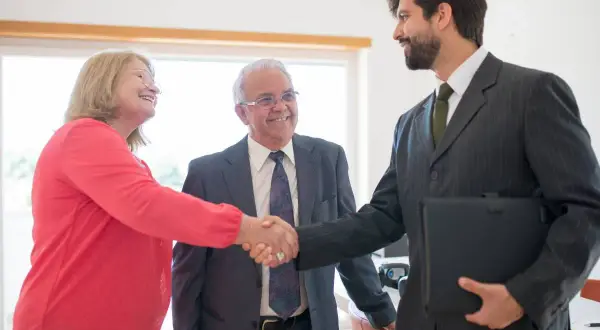 Coppia anziana stringe la mano a un consulente finanziario, discutendo del mutuo fino a che età.