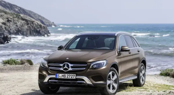 Brązowy, używany Mercedes GLC z salonu na tle morskiego krajobrazu. Idealny na wakacyjne wyprawy.