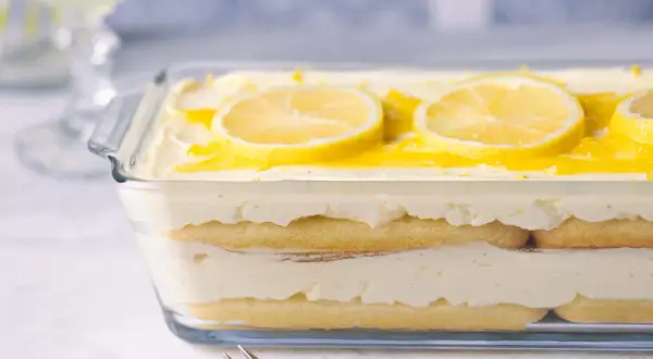 Ein erfrischendes Zitronen Tiramisu in einer Glasform, garniert mit Zitronenscheiben und einem Hauch von Zitronensauce.
