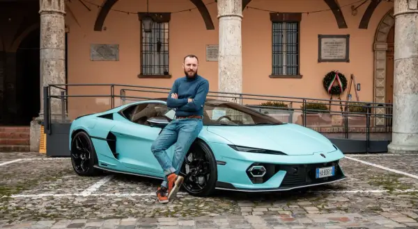 Mężczyzna opiera się o turkusowego Lamborghini Temerario na brukowanym dziedzińcu.