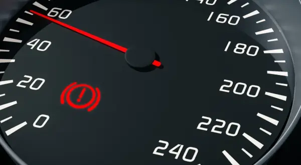 Tableau de bord d'une voiture avec le voyant frein à main reste allumé. L'aiguille du compteur de vitesse indique 60.