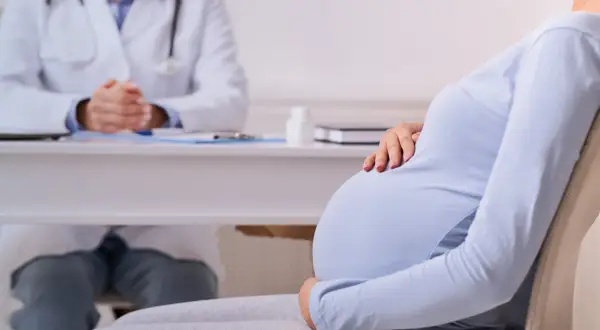 Mujer embarazada consulta a su médico por dolor de ovarios.