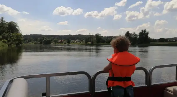 Dziecko w kamizelce ratunkowej podziwia widok na rzekę i lasy. Idealne miejsce na wypoczynek w agroturystyce "Bagna u Mańka".